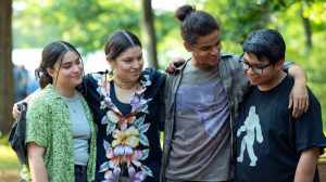Quatre adolescents en chemise décontractée se tiennent dehors, les bras autour de l'autre ;  toujours du film 