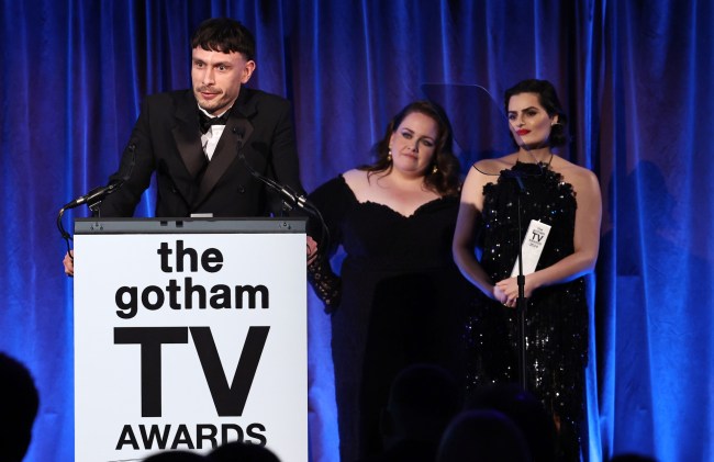 L'écrivain et acteur Richard Gadd porte un smoking et prend la parole sur le podium des Gotham TV Awards, avec les actrices Jessica Gunning et Nava Mau derrière lui.